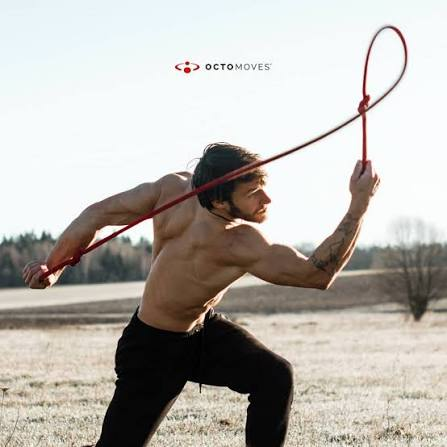 An athlete practicing rope flow outdoors with a red rope.